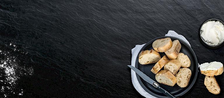 Black background with a bowl of baguette pieces